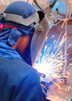 Welder in protective gear MIG welding a component with sparks visible
